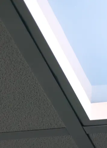 Detailaufnahme eines Deckenlichtpanels, eingebettet in eine Rasterdecke, das einen natürlichen Himmel simuliert.