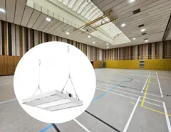 Eine Sporthalle mit hoher Decke und installierter LED-Beleuchtung, hervorgehoben durch eine Detailansicht einer einzelnen, abgehängten LED-Leuchte im Vordergrund.